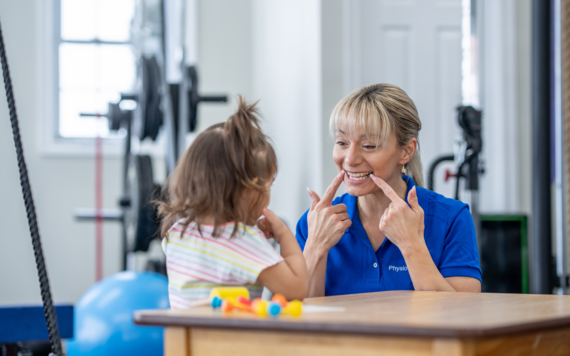 A speech and language therapist supporting a young child to make a speech sound
