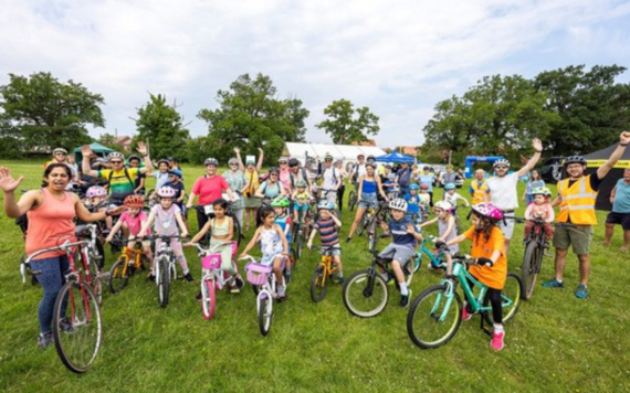 Adults and children posing in front of camera on their bicycles 