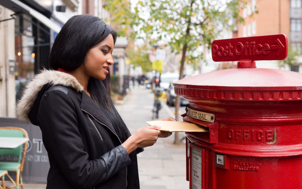 Someone posting their postal vote pack at a Royal Mail postbox