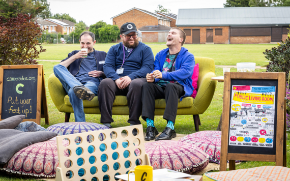 Three men sat chatting on a sofa at the outdoor cafe