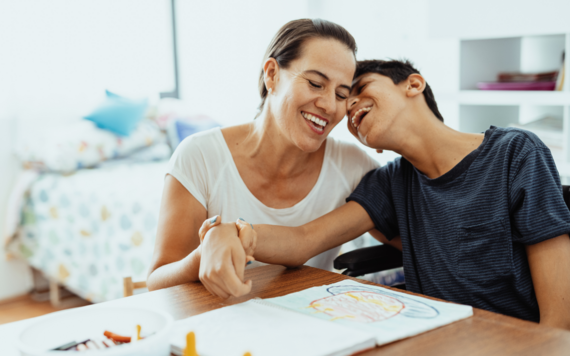 A mother and her son laughing as they read a book together 