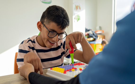 A young male sorts coloured pegs