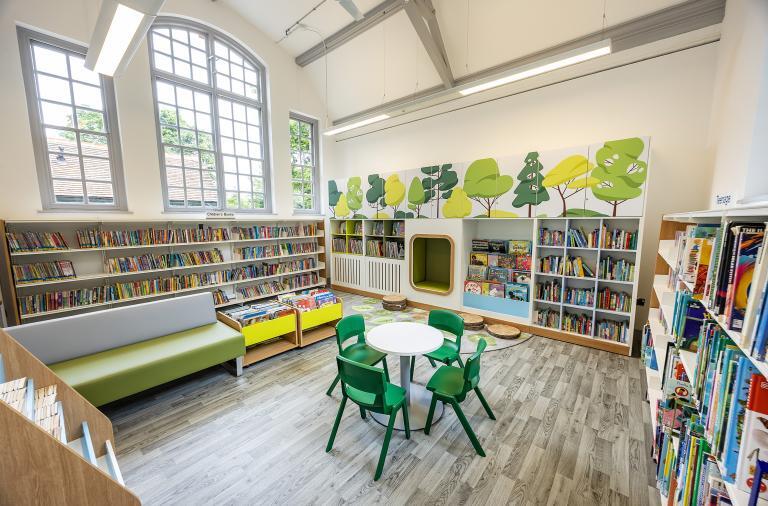 the children's area at Twyford library with a tall window and a colourful mural of trees and grass