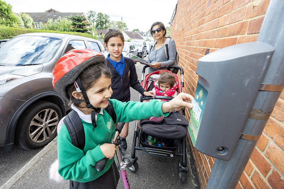 A girl in a safety helmet touches an electronic scorecard to a reader attached to a lamp post