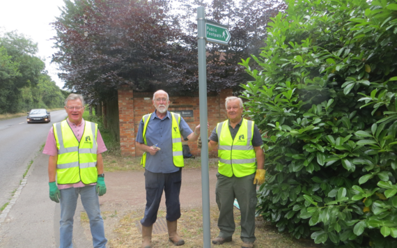 Loddon Valley Ramblers posing in front of camera with a new footpath sign