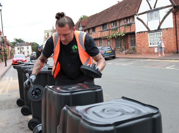 as bin delivery contractor attaching the wheels to an upturned black wheeled bin in Wokingham town centre