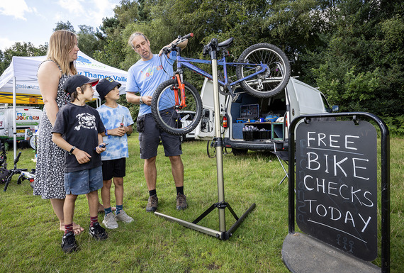 Bike mechanic servicing a bike and family watching