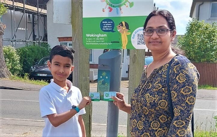 a son and mother hold up their score cards to a contactless reader as part of the Beat the Street game