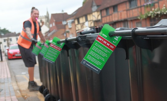 a row of black wheeled rubbish bins with tags saying "don't use me yet"