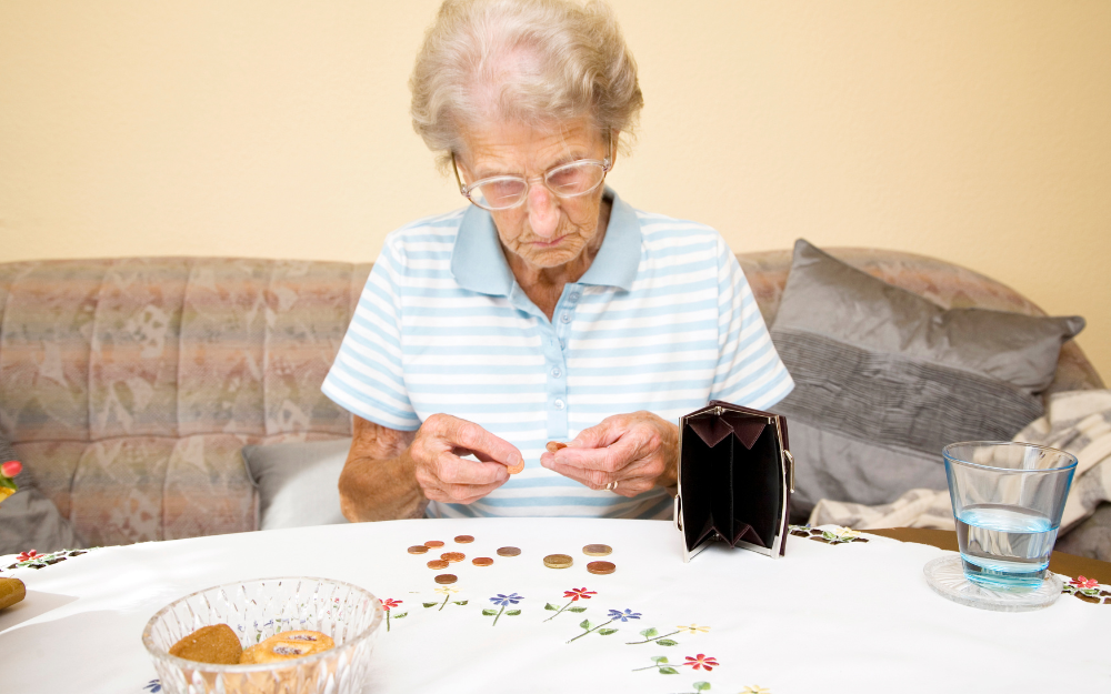 A pensioner counting coins from her purse at a table