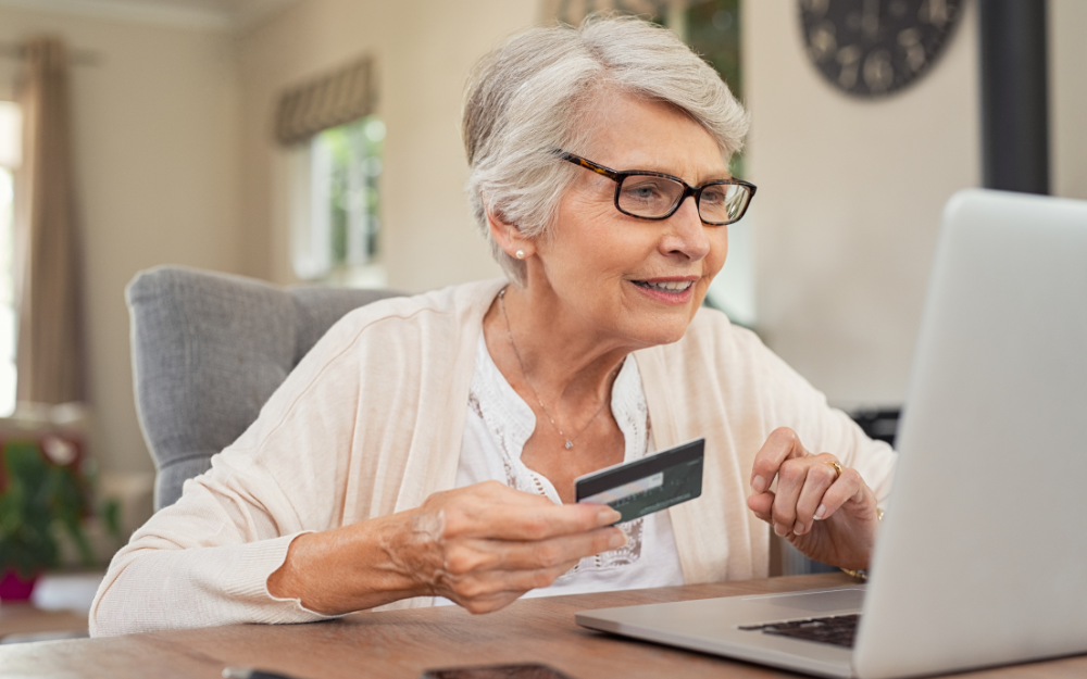 An older woman making an online card payment at her laptop