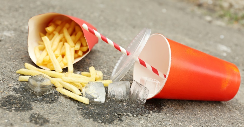a discarded and half eaten portion of chips next to a discarded soft drinks cup