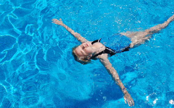 A young girl floats with arms outstretched in water