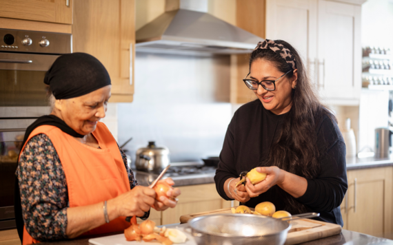Two ladies preparing food together and smiling