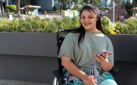 A teenage girl smiling and holding a phone