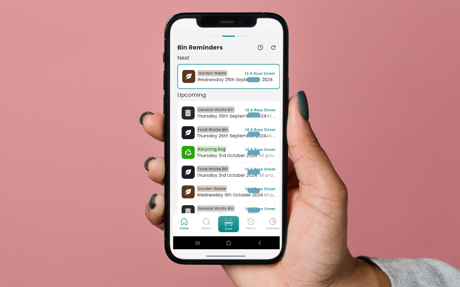 A hand holding a mobile phone displaying the Scrapp app with weekly bin reminders