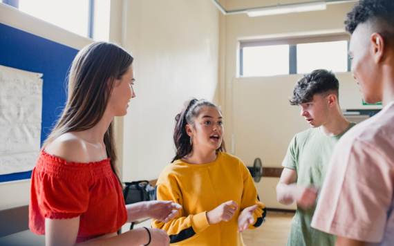 Four teenagers talking in a school hall