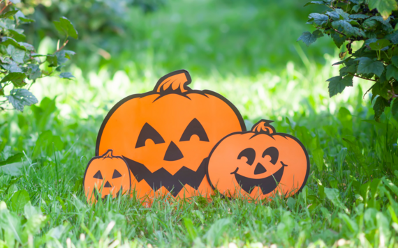 Three cardboard pumpkins of different sizes on the grass