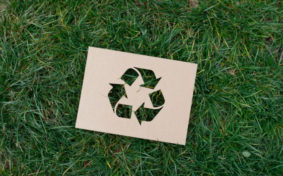 A recycling sign on the grass background 