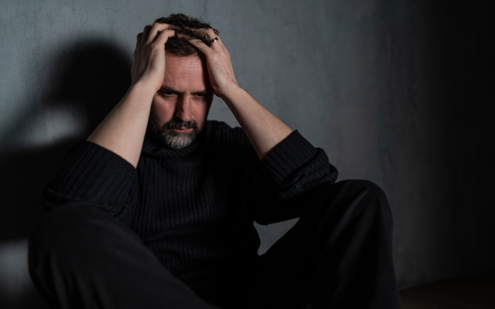 A man holds his head with his hands, in anguish 