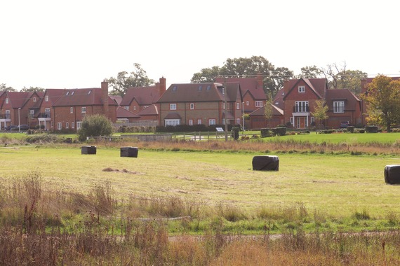 a row of new houses in the background with newly created public green space and hay bales in the foreground