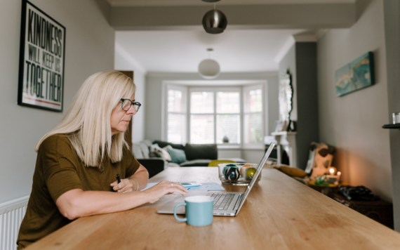 Lady at dining table looking at her laptop