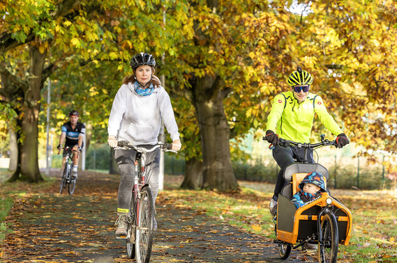 Two cyclists and one cyclist with a child in a cargo bike