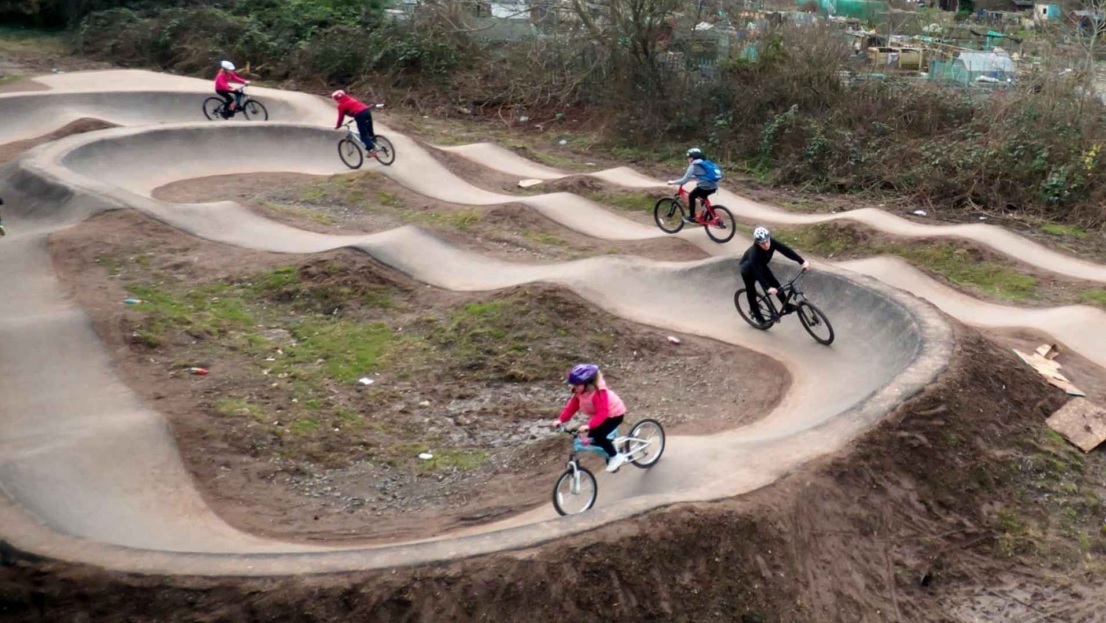 an artist's impression of a dirt track with children cycling around it on BMX bikes
