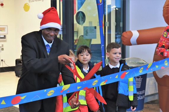 A smiling man in a Santa hat poses with a big pair of scissors and a ceremonial ribbon at the new Aldi in Shinfield