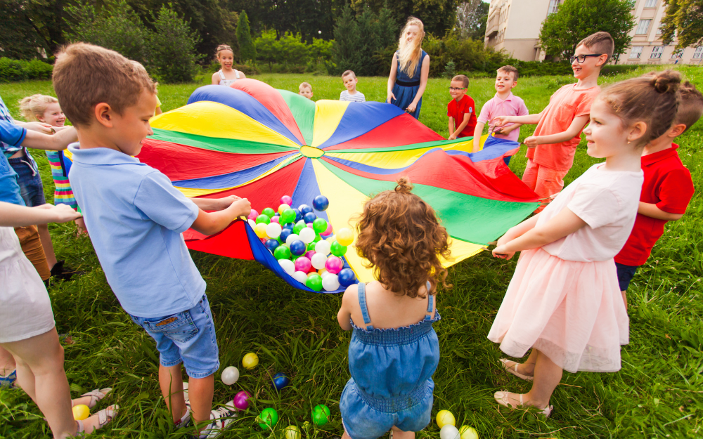 A group of young children playing with a colourful parachute outside