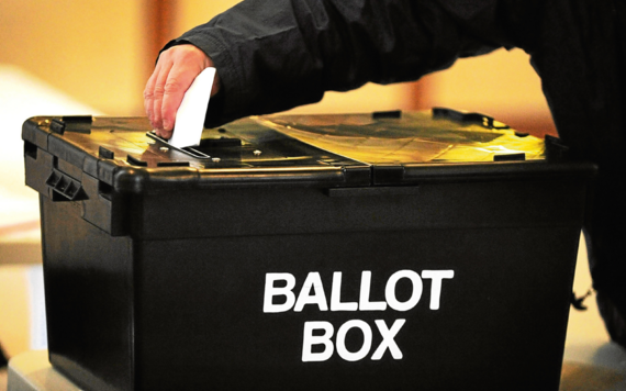 A vote card being posted through a ballot box