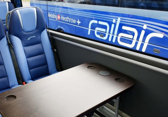 interior shot of a RailAir coach with blue leather seats and a table with drinks holders