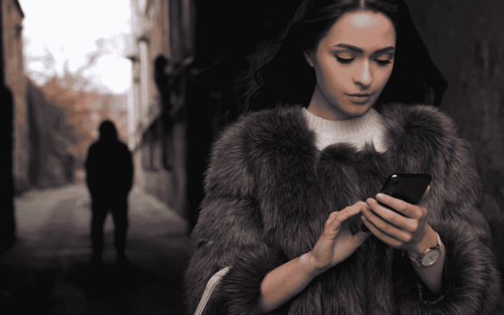 Man in background watching woman on her phone