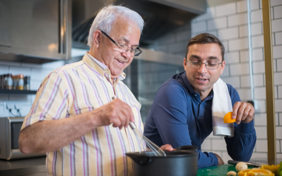 Young man helping and older man cook in his kitchen