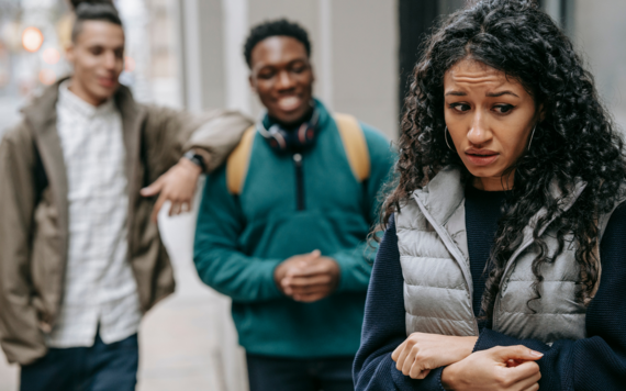 Nervous looking woman with two men laughing in the background