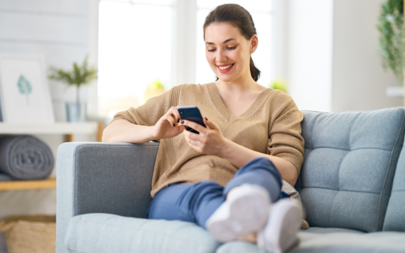 Someone checks their Council Tax bill on their phone while sat on the sofa