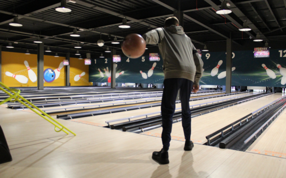 Person with their back to the camera in a bowling alley, about to throw their ball