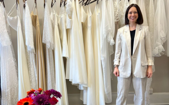 Lucy Kern posing in front of some bridalwear