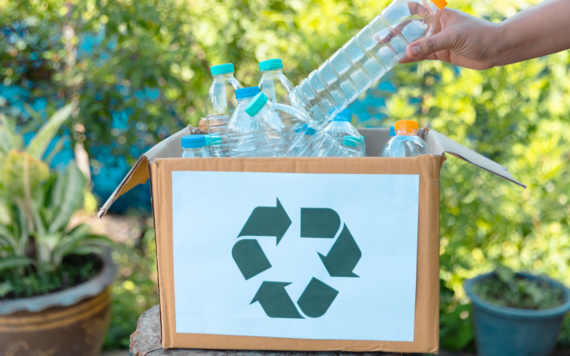 Some plastic bottles in a box that has a recycling symbol in the front