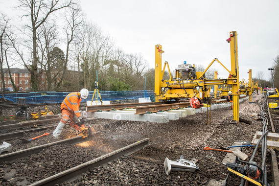 men in orange high vis jackets working on the railway with a large construction vehicle