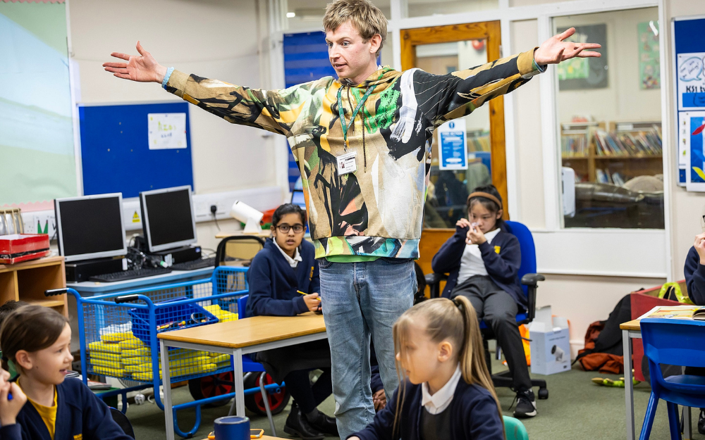 A man stretches his arms out wide during a creativity workshop for the Forest of Imagination