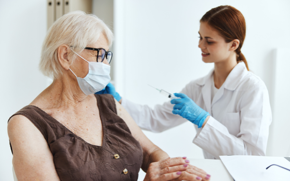 An older person gets a vaccination in their arm