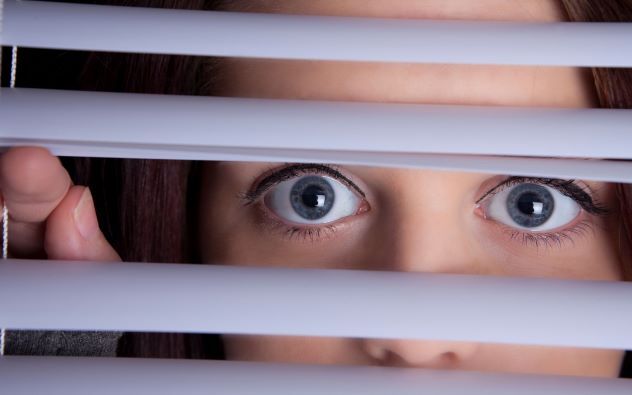 woman looking through blinds
