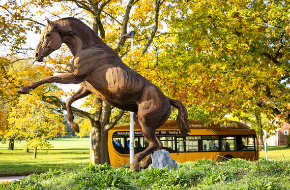 a large bronze statue of a horse with a number 3 leopard bus passing behind it, out of focus