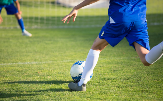 Footballer's legs shown shooting a ball towards a goal