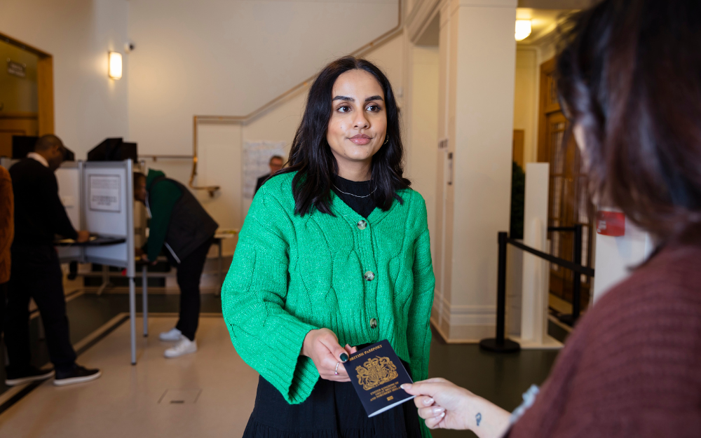 Person passing over their passport for ID check at a polling station