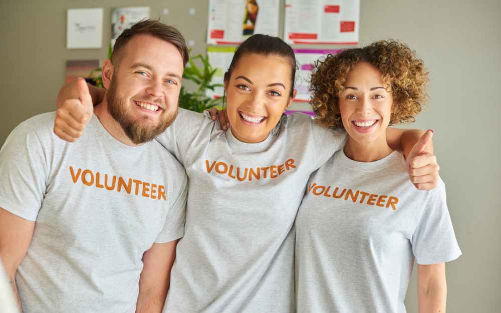 Three volunteers with their arms around each other, smiling