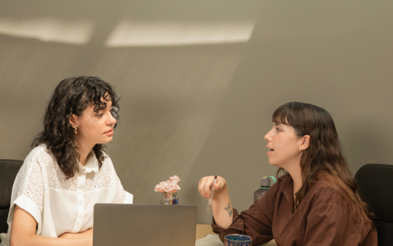 Two young ladies talking and looking at a computer together