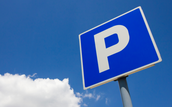A parking sign with a clear blue sky behind it