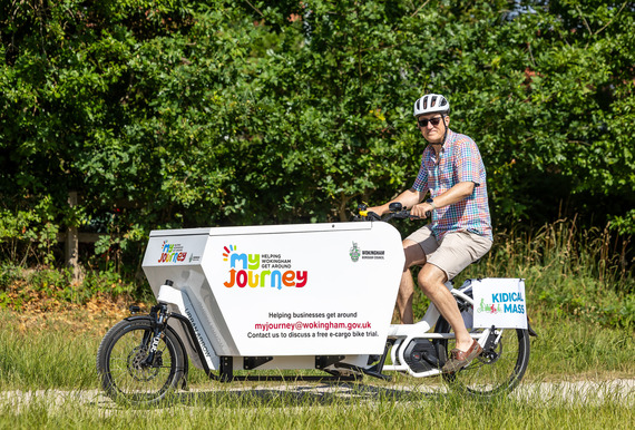 an older man riding a large electric cargo bike with a storage box on the front and the My Journey logo